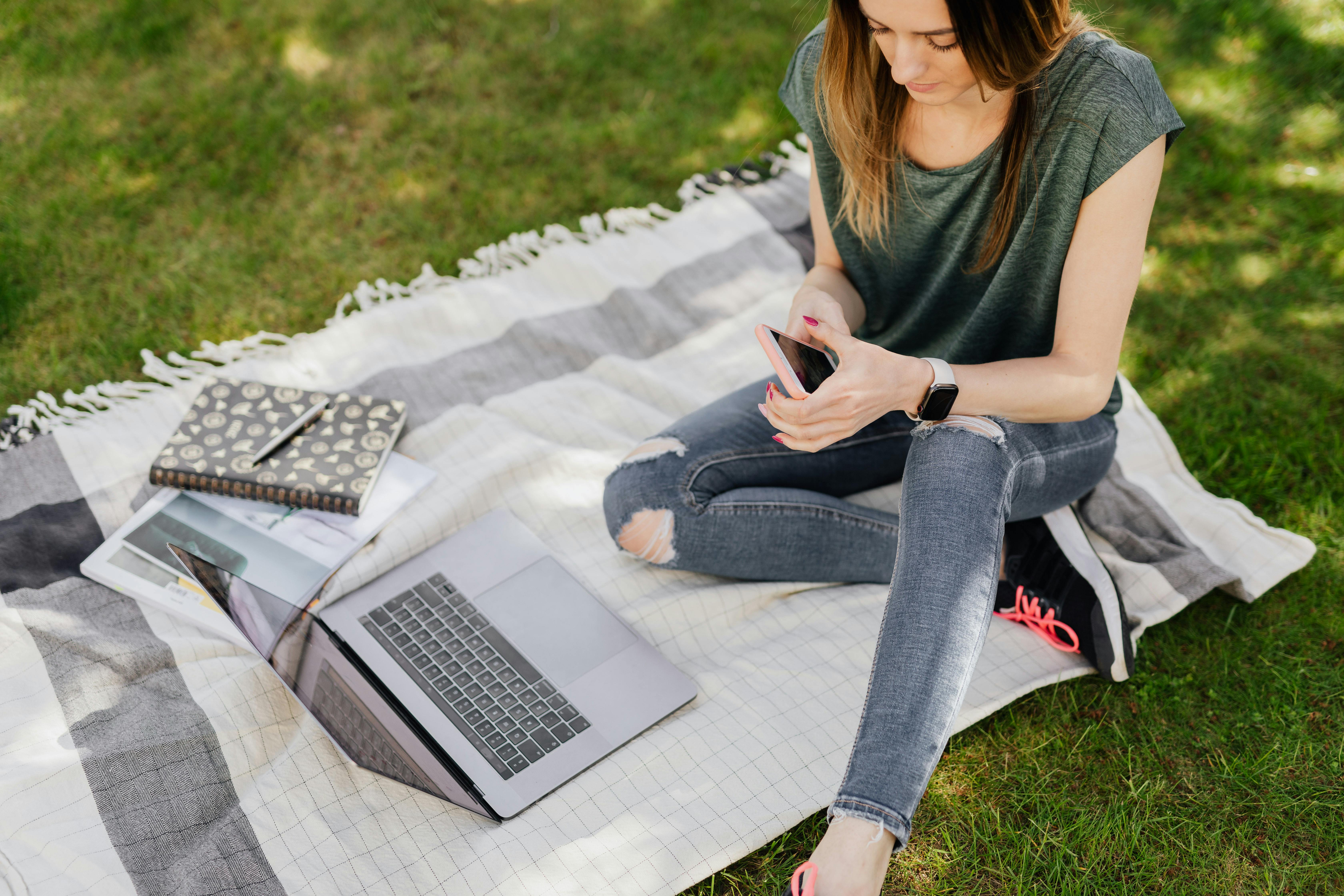 Person mit Smartphone und Laptop in einer ruhigen Alltagsszene als Sinnbild für pragmatische IT-Unterstützung